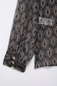 Detailansicht eines Chiffon-Hemdärmels mit Vintage-Muster und Goldknöpfen