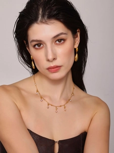 Close-up of 18K gold plated teardrop tassel earrings and pearl necklace set on model