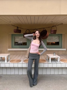 Detail of pink crop top with grey knit bolero and flared trousers in an outdoor setting