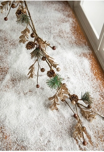 Détail des feuilles dorées pailletées et pommes de pin naturelles sur une guirlande de Noël
