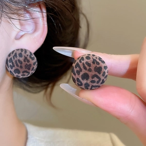 Detailed macro of round leopard print earrings with a soft flocked matte texture