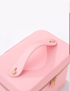 Detailed close-up of pink cross-grain leather makeup case with gold hardware and handle