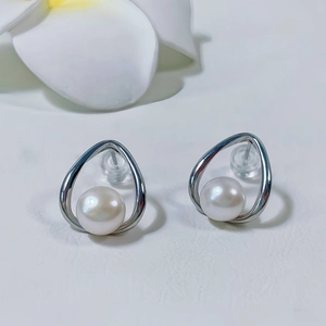 Dettaglio orecchini a nodo geometrico con perle bianche e montatura in argento lucido