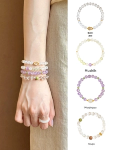 Detailed macro view of natural amethyst and green stone beaded bracelets with gold charms