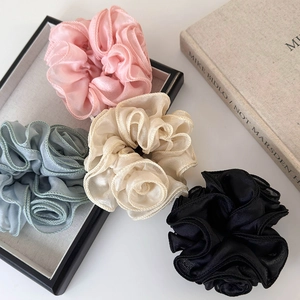 Floral organza hair scrunchies in pastel colors on a display tray for elegant styling