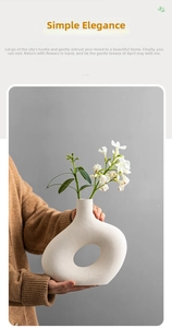 Close-up of a hollow circular ceramic vase with grainy texture held by a person