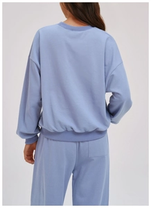 Back view detail of comfortable light blue crewneck sweatshirt with ribbed cuffs and hem