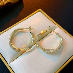 Élégantes boucles d'oreilles doubles anneaux dorées avec zircons dans un écrin
