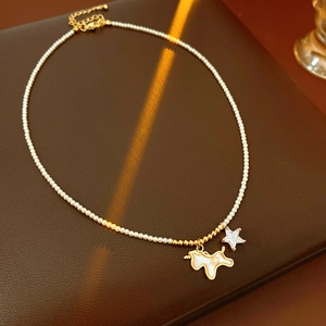 Detail of pearl necklace with white shell unicorn and crystal star pendant on leather