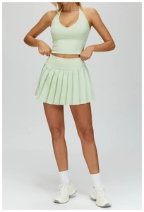 Detail of mint green pleated tennis skirt and halter neck sports bra with white sneakers