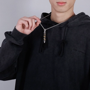 Detail of silver bullet pendant with golden dragon wrap on a male model neck