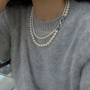Detail of elegant double-layer pearl necklace with silver infinity clasp on a soft sweater