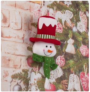 Detail of a plush snowman ornament with red hat and green scarf on a festive tree