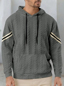Detail of grey cable knit hoodie featuring contrasting black and white sleeve stripes