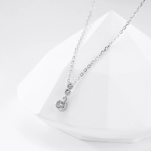 Macro shot of polished silver pendant with three vertically aligned sparkling zircons