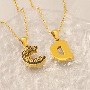 Close-up of gold letter C and D pendants with black bark texture on fine chain