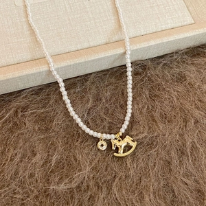 Detail view of pearl necklace with gold rocking horse charm and sparkling zircon pendant