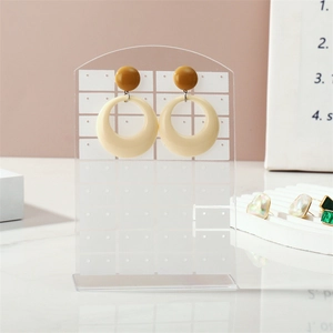 Mustard yellow and creamy white geometric resin earrings on a clear acrylic display stand
