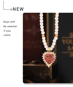 Close-up of heart-shaped red zircon pendant with pearl chain and gold metal accents