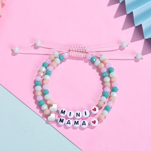 Macro shot of MAMA and MINI beaded bracelets with pastel crystals on pink and blue backdrop