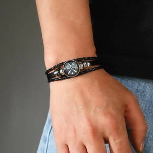 Détail d'un bracelet en cuir noir tressé avec un motif de raquette de badminton blanc