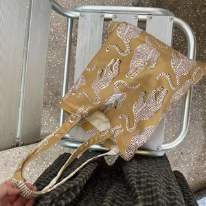 Détail du sac cabas en coton avec imprimé léopard et étiquette tissée sur chaise en métal