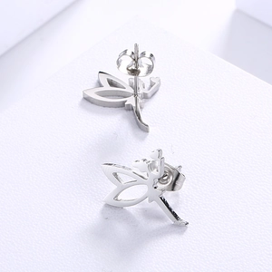 Close-up of silver dragonfly stud earrings with shimmering stones on a white textured base