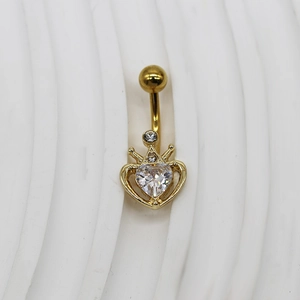 Détail du piercing de nombril doré avec cristal en forme de cœur et couronne polie