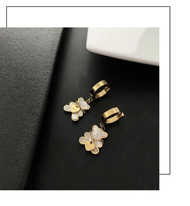 Detailed macro view of gold bear earrings with shell texture and engraved love heart charm