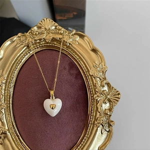 Macro view of French retro white enamel heart pendant necklace with gold detail