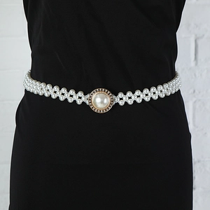 Detail of multi-row pearl waist belt with a golden rhinestone buckle on a black dress