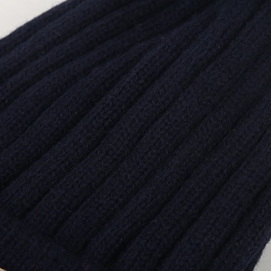 Gros plan du tissu en maille côtelée bleu foncé montrant la texture épaisse du bonnet