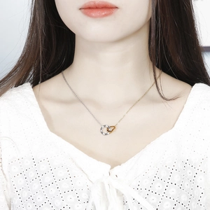 Detail shot of a dual-tone interlocking necklace with heart and crystal ring pendants