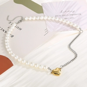 Detail of a pearl and silver chain necklace with a golden heart pendant on a card