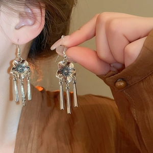 Detail of silver bamboo flower earrings with long tassels and pearls on a model