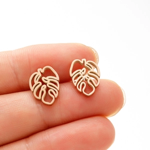 Detailed close-up of rose gold monstera leaf stud earrings held to show compact size
