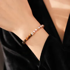 Tiger eye stone and pearl beaded bracelet with gold accents on model wrist