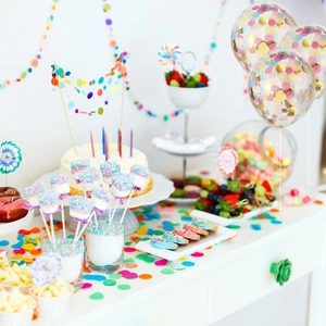 Vibrant party dessert table with colorful balloons, bunting banners, and cake toppers decoration