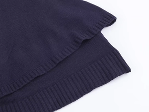 Detailed close-up of the ribbed high-low hem on a dark blue knitted cape top garment