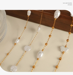 Macro view of 18k gold chain necklace with irregular baroque white pearls and butterfly charms