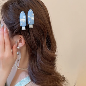 Close-up of a model wearing two light blue floral teardrop hair clips on brunette hair
