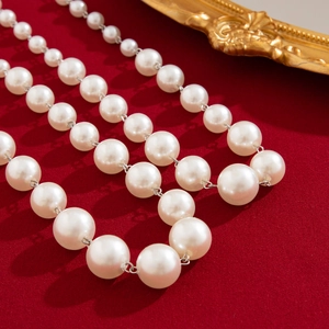 Close-up of multi-layer white faux pearl necklace with glossy finish on red fabric