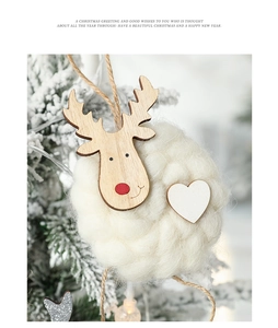 Detail eines Holz-Rentier-Anhängers mit weichem Plüschsockel an einem verschneiten Weihnachtsbaum