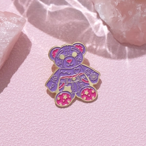 Detail of purple enamel bear brooch with heart and star patterns on pink crystal background
