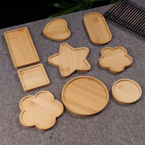 Various shapes of bamboo wooden coasters and DIY craft trays on a grey linen fabric surface