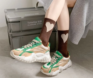 Detail view of coffee brown mid-calf socks with heart pattern and retro sneakers