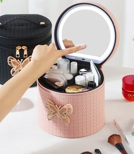 Detalle de neceser redondo de PU rosa con espejo LED y aplique de mariposa