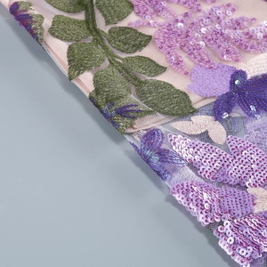 Detailed close-up of purple floral embroidery and sequins on mesh fabric dress