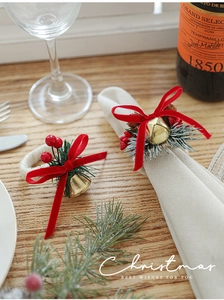 Close-up of Christmas napkin ring with red bow, pine cones and berries on dining table