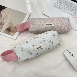 Detailed view of floral canvas pencil cases with fabric handles on a white desk
